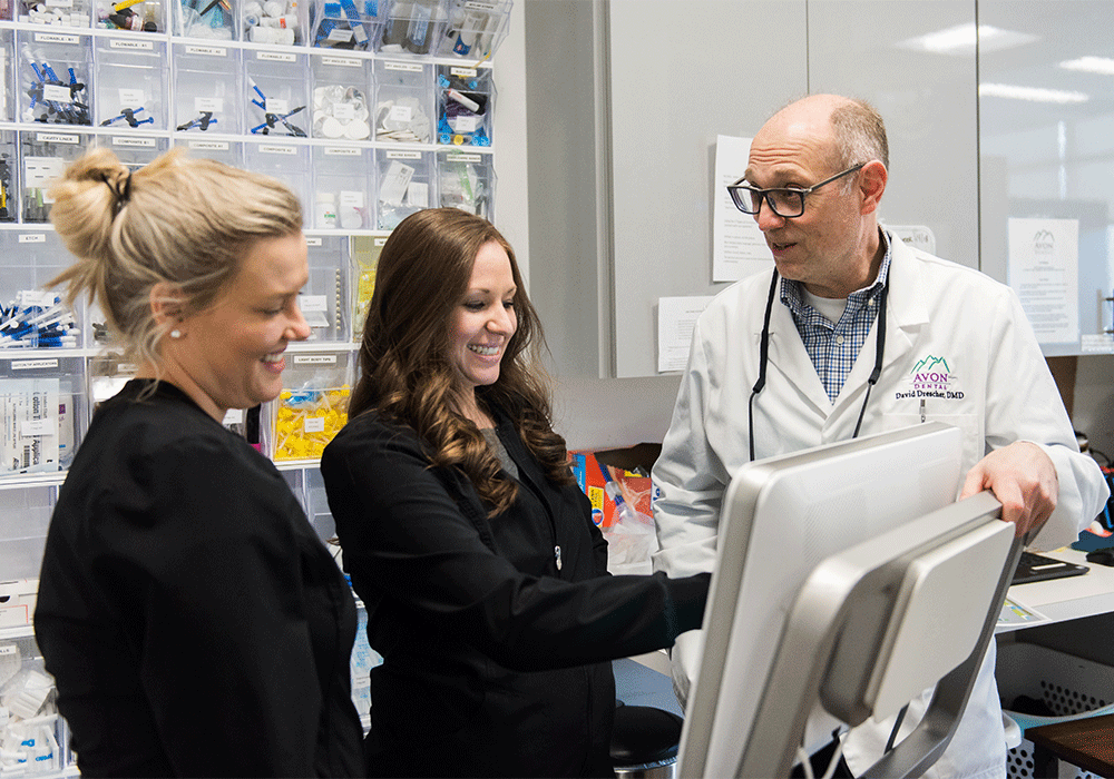 Dr Drescher and Dental Hygienists talking and smiling while reviewing scans on a computer screen at Castle Peak Dental in Eagle, CO.