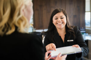 girl smiling and handing a form to client